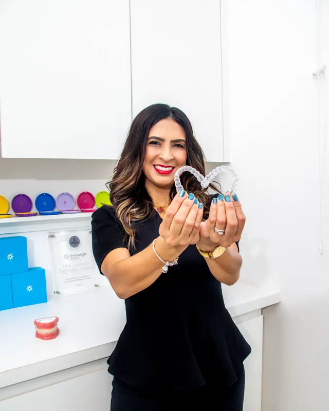 La doctora muestra un alineador transparente; detrás, los estuches de colores