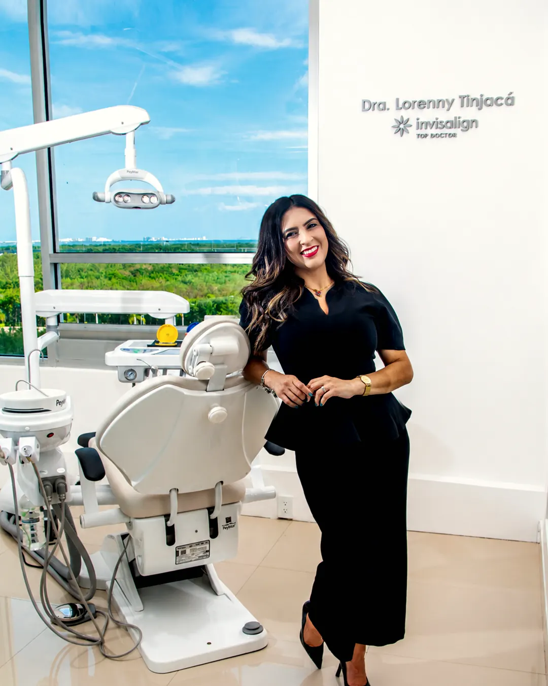 La Dra. Lorenny Tinjacá junto al sillón, bajo el letrero de Invisalign Top Doctor