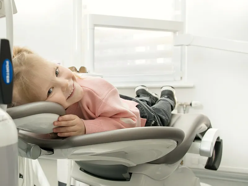Una niña recostada en el sillón dental, sonriendo tranquila