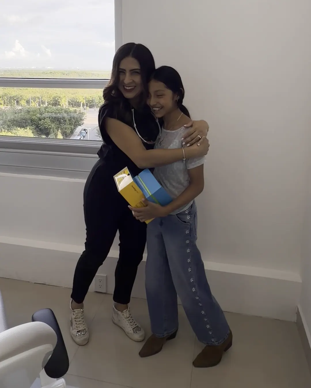 La Dra. Lorenny Tinjacá abraza a una paciente que recibe su caja de Invisalign First