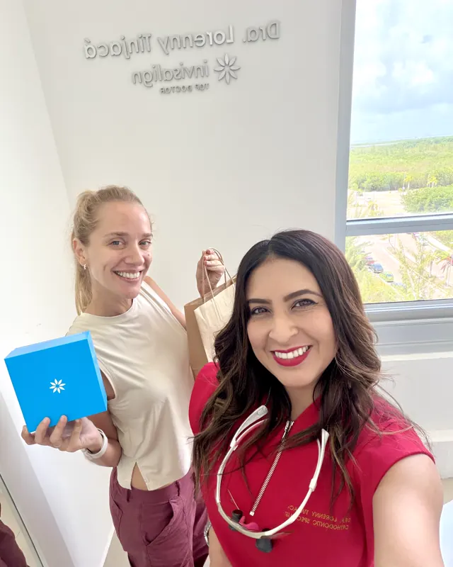 Selfie de la doctora con una paciente que sostiene su caja de Invisalign