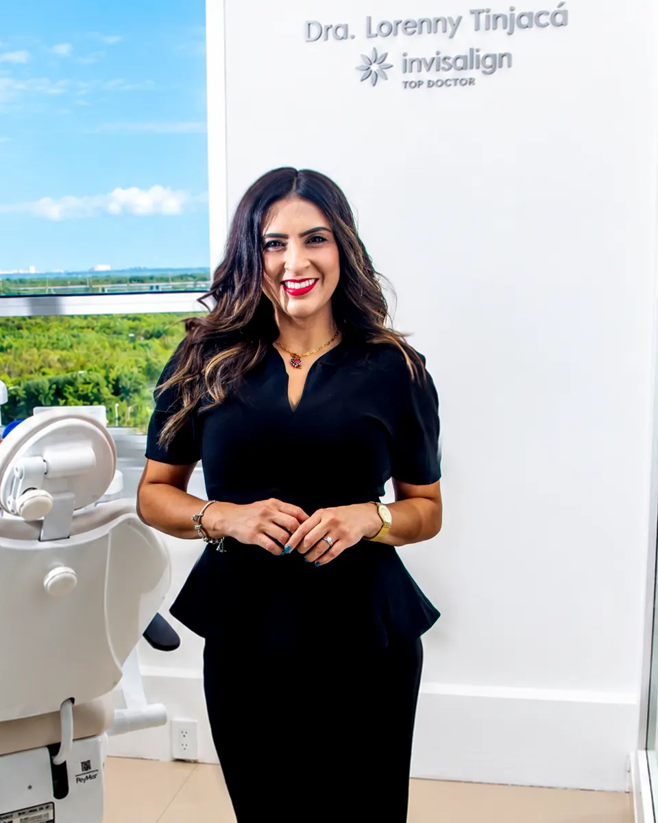 La Dra. Lorenny Tinjacá en su consultorio, frente al letrero de Invisalign Top Doctor