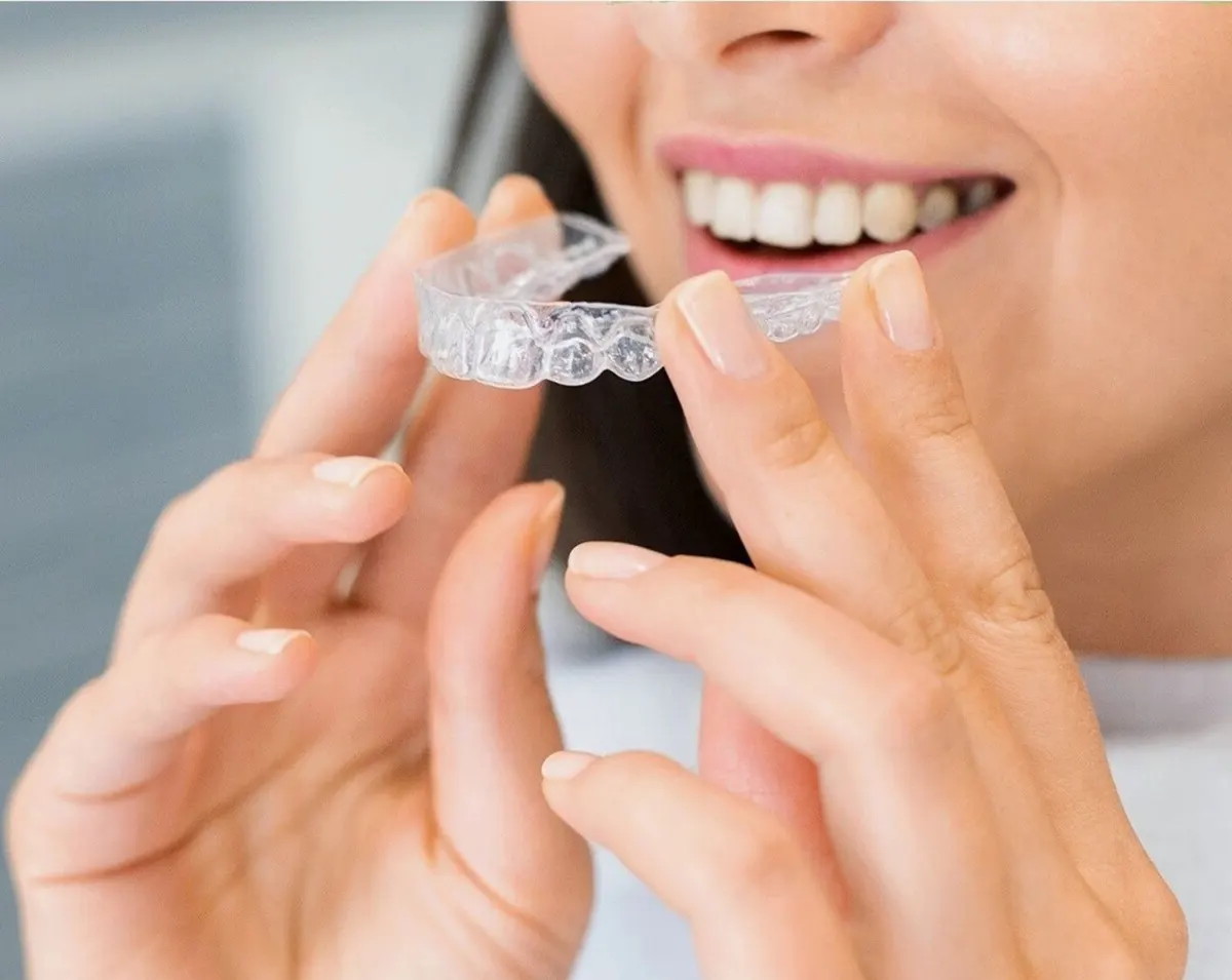 Mujer sonriendo mientras se coloca un alineador transparente